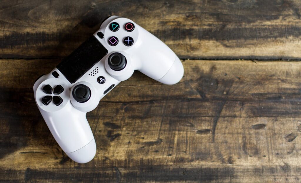 pexels-photo-275033 White game controller resting on a rustic wooden surface, top view.